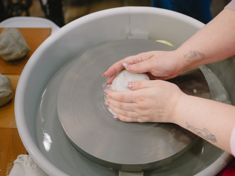 Person shaping clay on pottery wheel
